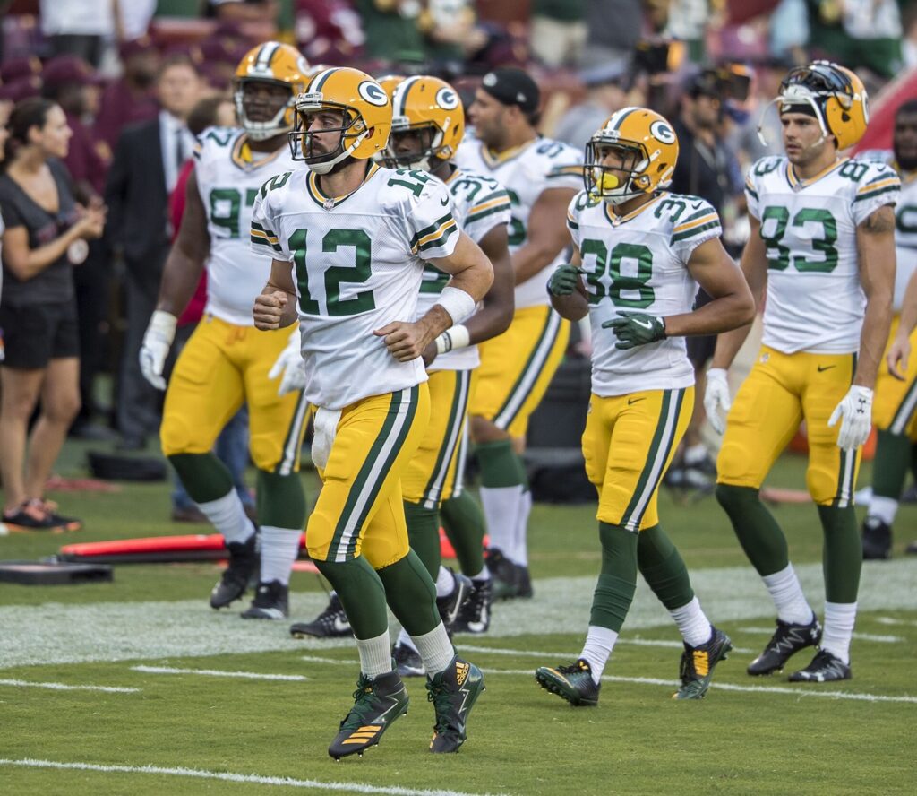 Aaron Rodgers (12) jogs onto the field with Packers teammates before a preseason game in August 2017