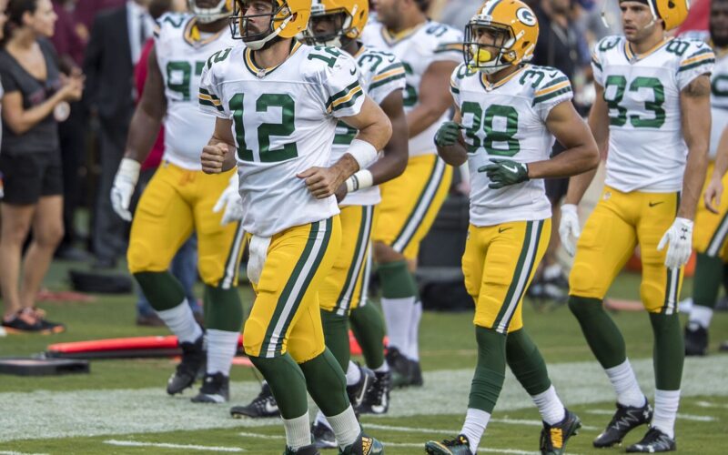 Aaron Rodgers (12) jogs onto the field with Packers teammates before a preseason game in August 2017