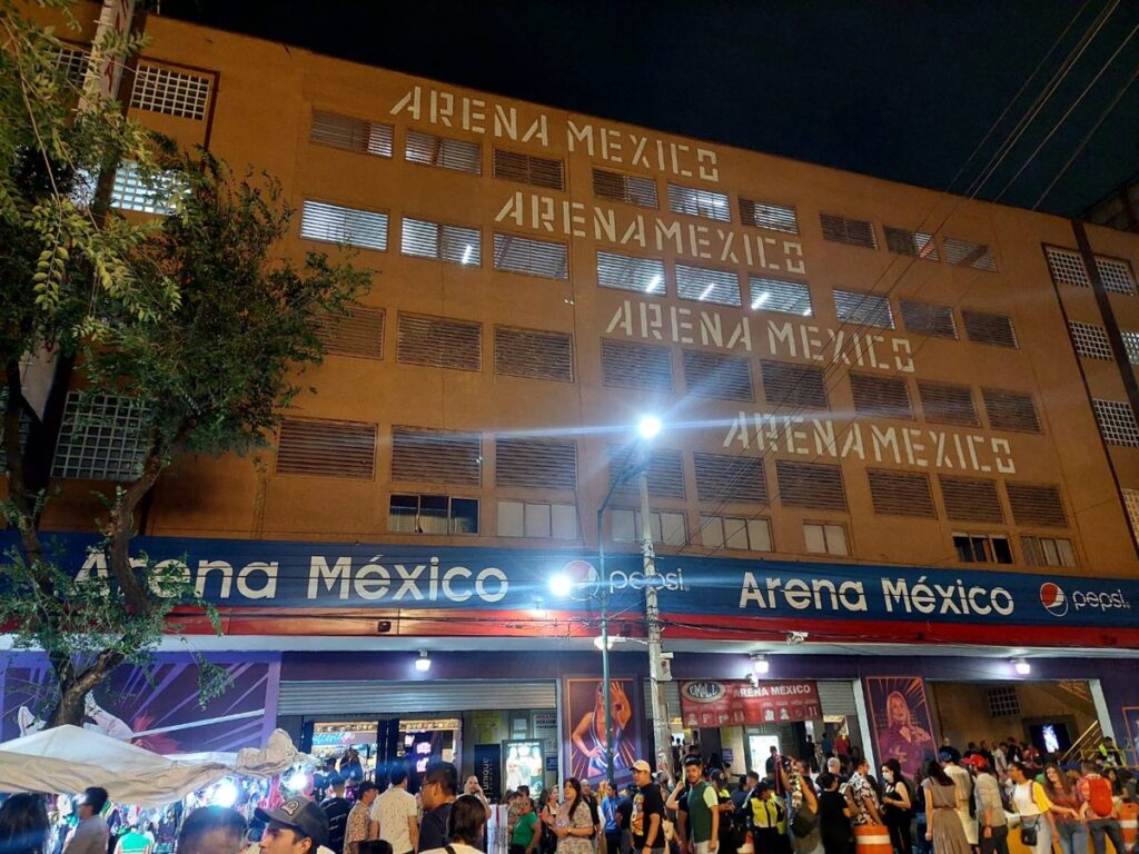 Fans gather at night outside Arena México in Mexico City, its name lit up on the facade