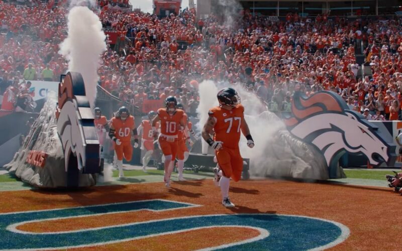 Broncos players run onto the field through smoke at Empower Field at Mile High