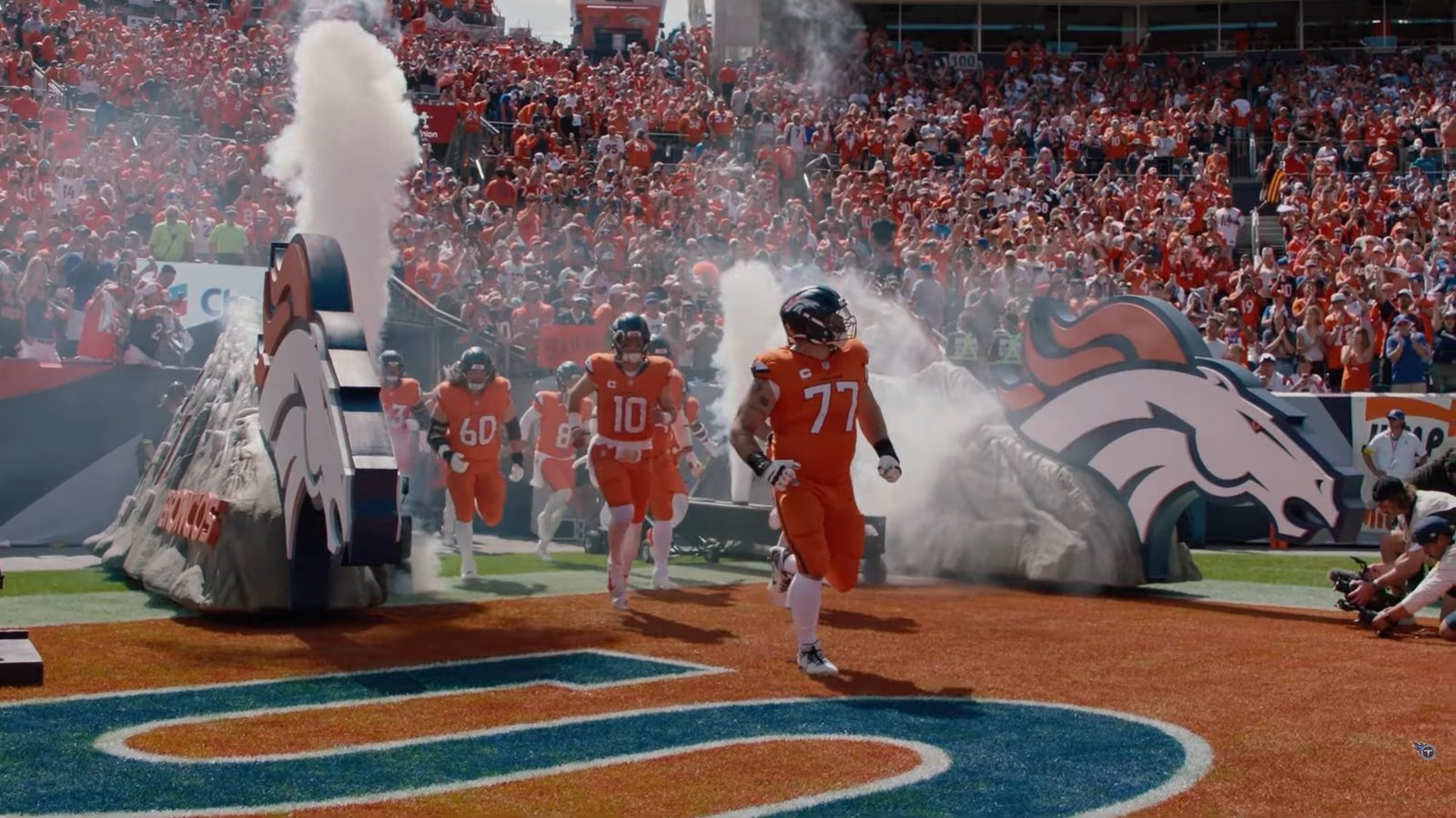Broncos players run onto the field through smoke at Empower Field at Mile High