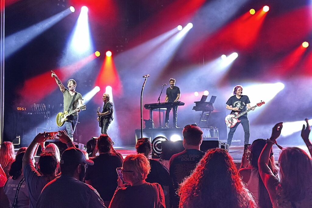 The Goo Goo Dolls perform on a concert stage under red and white lights