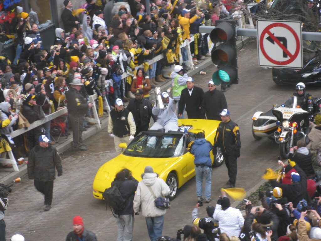 James Harrison holds the Lombardi Trophy while riding in a yellow convertible through crowds at the Steelers' Super Bowl XLIII parade in Pittsburgh