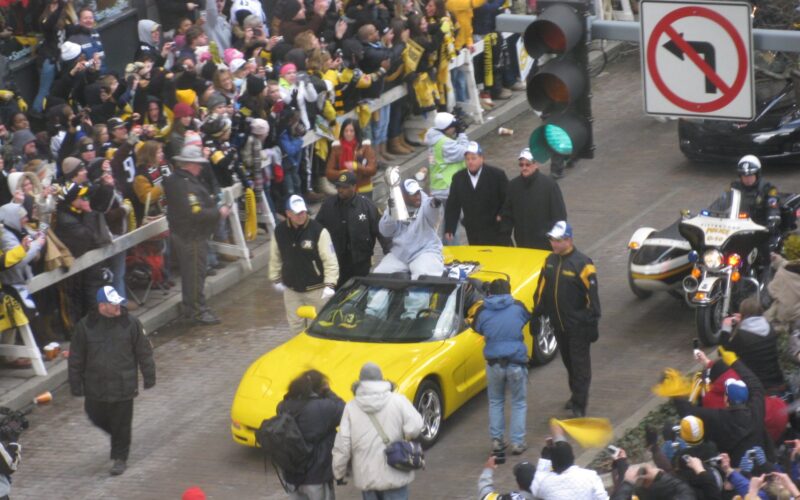 James Harrison holds the Lombardi Trophy while riding in a yellow convertible through crowds at the Steelers' Super Bowl XLIII parade in Pittsburgh