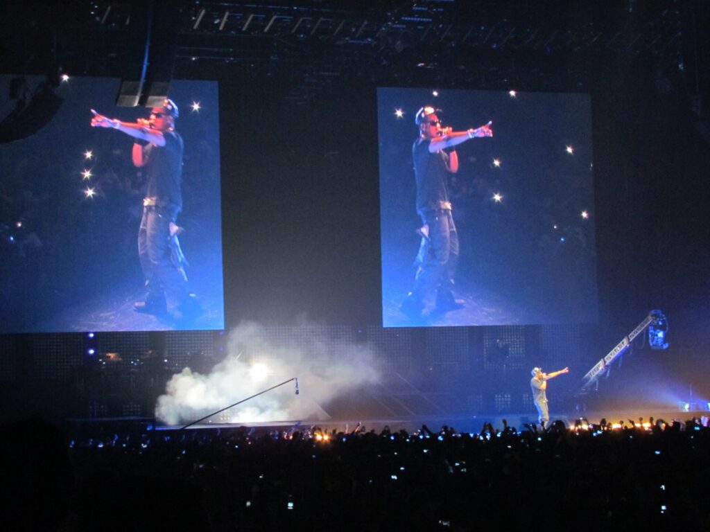 Jay-Z performing on stage under two large video screens at The O2 Arena in London in 2012
