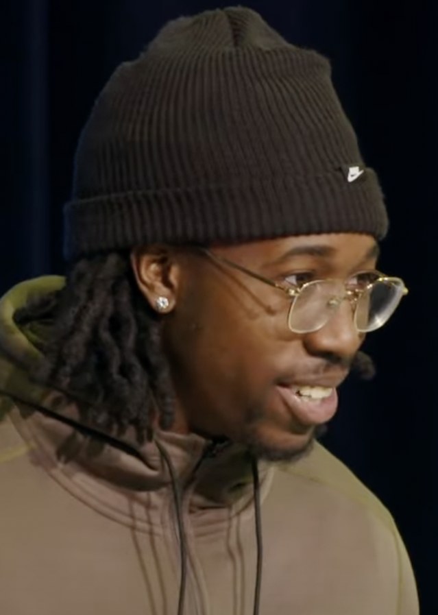 Joey Porter Jr. in a knit hat and glasses speaking to reporters