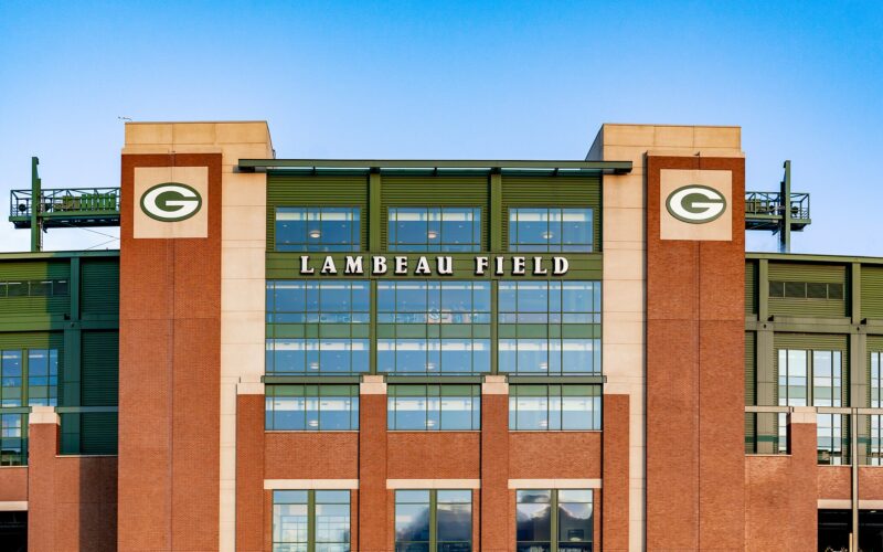 The brick facade of Lambeau Field in Green Bay, Wisconsin, with the stadium name and two Packers G logos.