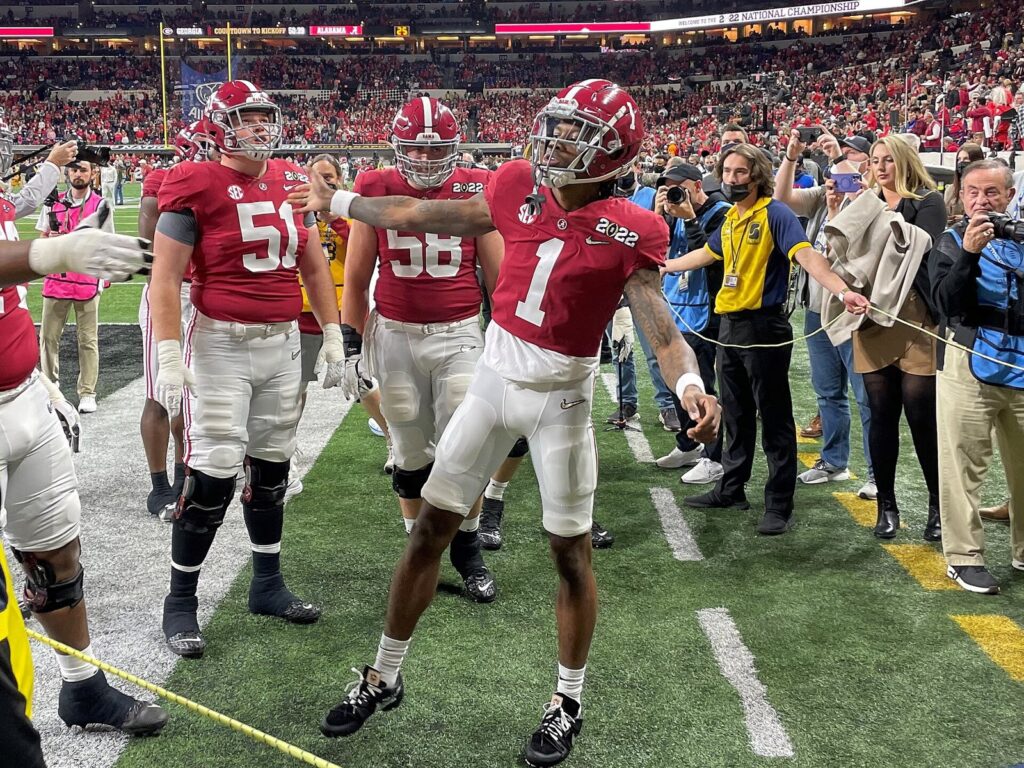 Jameson Williams in an Alabama uniform high-fives a teammate on the field