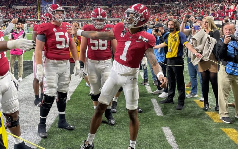 Jameson Williams in an Alabama uniform high-fives a teammate on the field