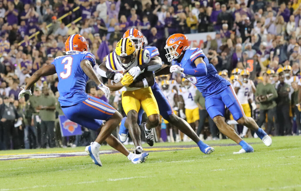 Malik Nabers wearing LSU No. 8 carries the ball between Florida defenders in 2023