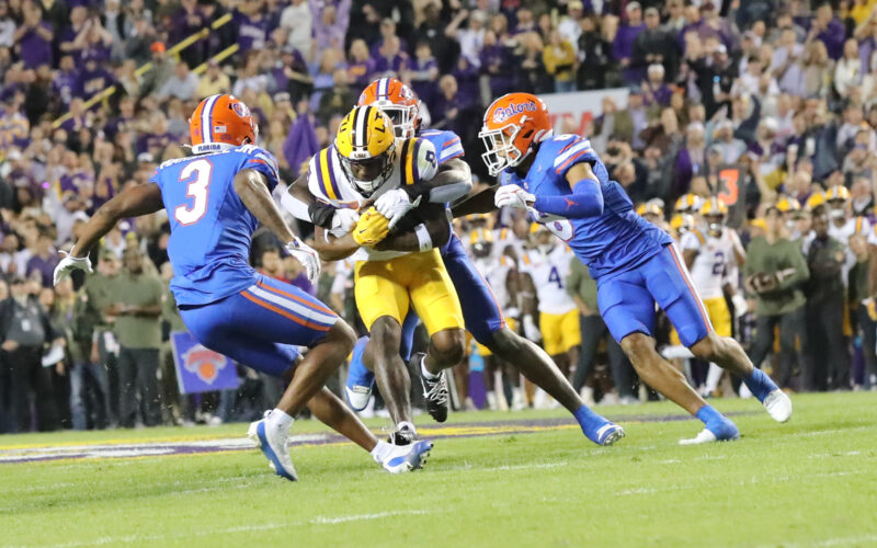 Malik Nabers wearing LSU No. 8 carries the ball between Florida defenders in 2023