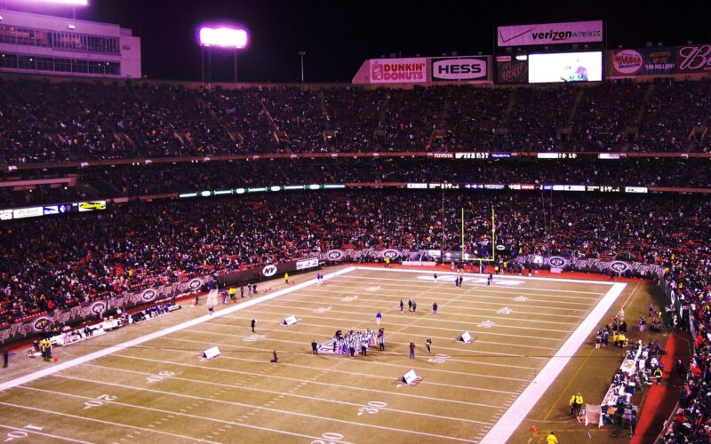 The field at Giants Stadium during a night game, with Jets end-zone banners and a full crowd