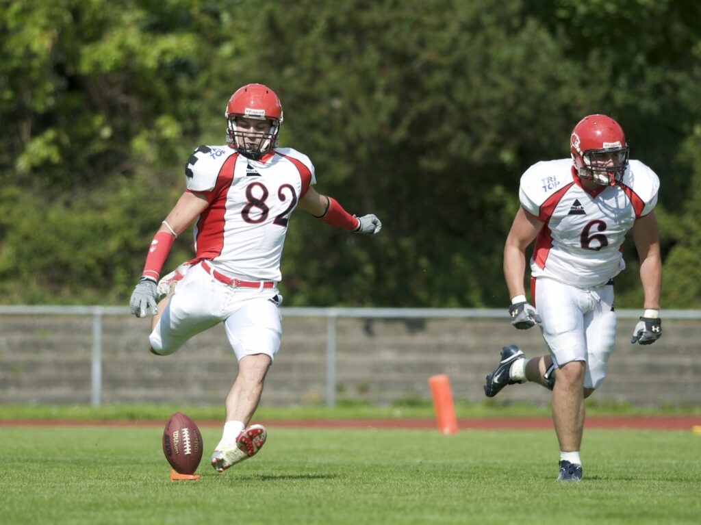 Kicker boots the opening kickoff as coverage and return teams sprint downfield