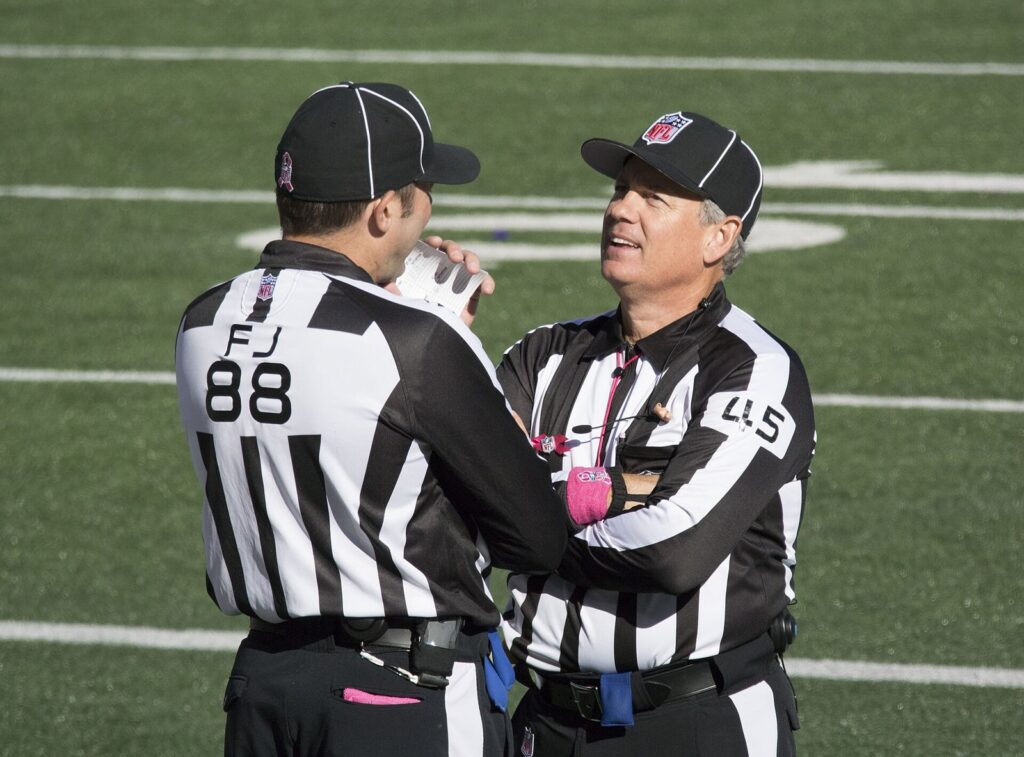 Two NFL game officials talking on the field before a game