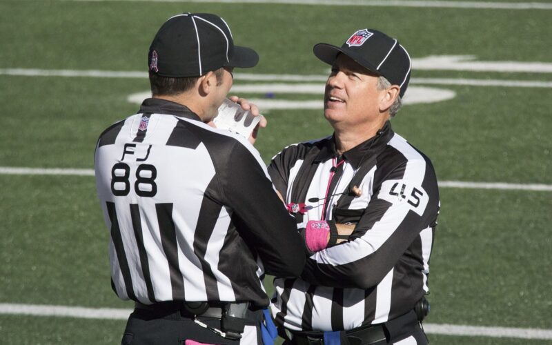 Two NFL game officials talking on the field before a game