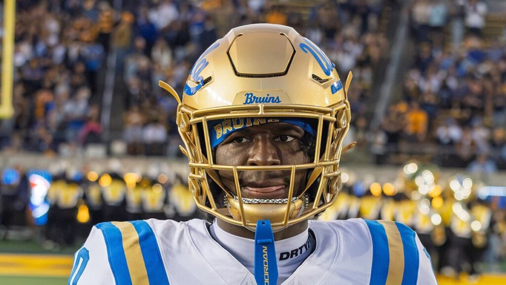UCLA linebacker Sammy Omosigho, No. 10, in a gold helmet and white jersey on the sideline at California in September 2026.