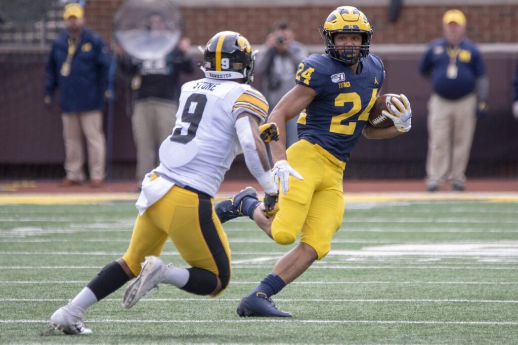 Zach Charbonnet, No. 24 in a blue Michigan jersey, runs with the ball past an Iowa defender in October 2019